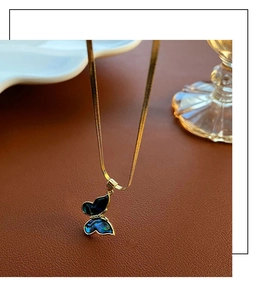 Detail of a butterfly pendant with blue abalone shell on a gold snake chain necklace