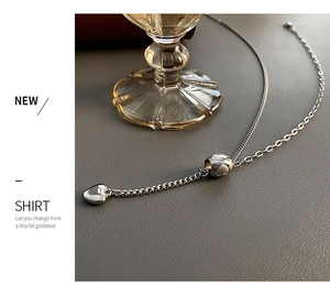Detailed close-up of a silver heart pendant necklace with metallic luster and chains