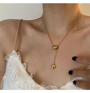 Detail of a gold heart pendant necklace on collarbone with adjustable slider bead