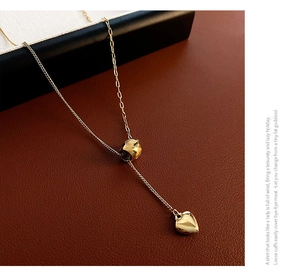 Detailed macro shot of a gold Y-shaped titanium steel necklace with double heart pendants