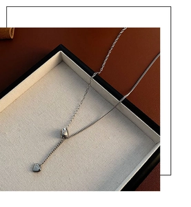 Detailed shot of silver heart pendant necklace on textured tray with contrast lighting