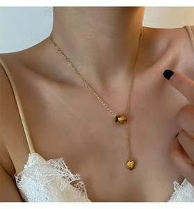 Close-up of golden heart pendant necklace with thin chain on female model neck