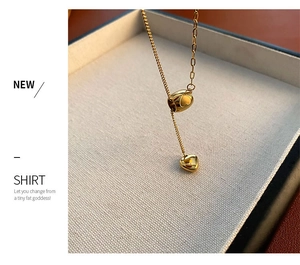 Close-up of golden titanium steel heart necklace with mixed chain texture on jewelry tray