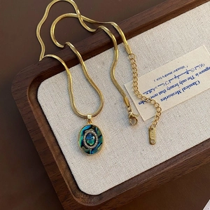 Close-up van gouden slangenketting met abalone schelphanger en K18-merklabel