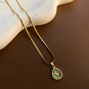 Détail du pendentif goutte en nacre d'abalone dorée sur une chaîne serpent plate