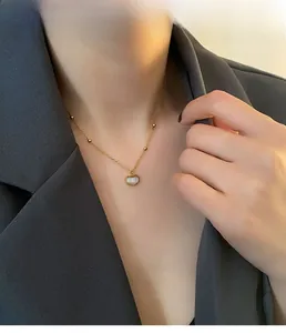 Gros plan du collier cœur en acier titane doré avec nacre porté par un mannequin