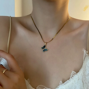 Gold butterfly abalone shell pendant on a snake chain necklace worn by a model