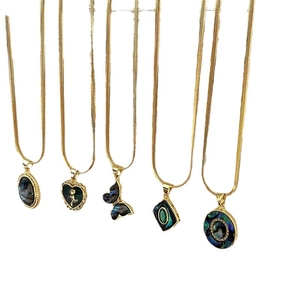 Cinq colliers dorés avec pendentifs en nacre d'abalone en formes d'ovale, cœur et papillon