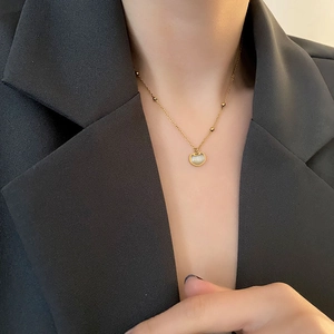 Collier chic en acier titane doré avec pendentif chat et opale sur un costume noir