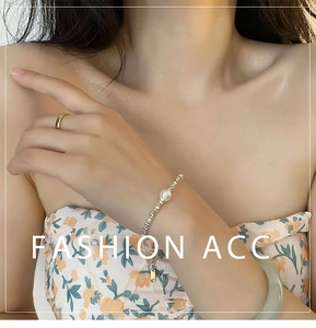 Détail d'un bracelet de perles argenté avec maillons géométriques sur le poignet