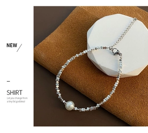 Vue détaillée du bracelet à billes argentées avec perle blanche centrale sur velours