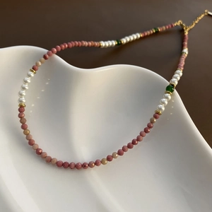 Collar artesanal de cuentas rosas y perlas presentado en bandeja de cerámica
