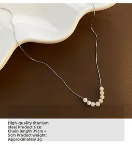 Dettaglio della collana in acciaio al titanio con sette perle di conchiglia su un piatto