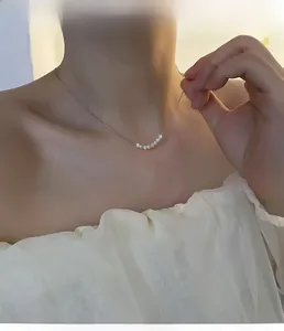 Dettaglio dell'elegante collana con ciondolo di perle indossata sulla clavicola