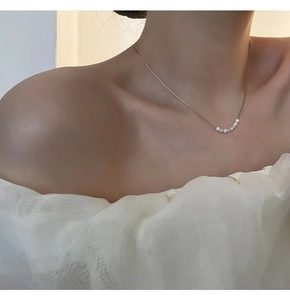 Dettaglio della collana minimalista in acciaio al titanio con sette perle bianche sulla catena