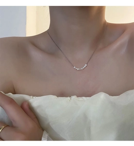 Dettaglio di una collana in acciaio al titanio con sei eleganti perle bianche su catena