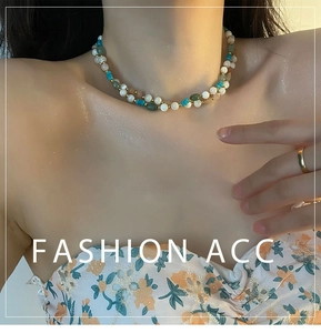Close-up of double-layered beaded necklace with pearls, turquoise, and green stones