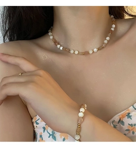 Detail of beaded strawberry quartz necklace and bracelet set with golden spacer beads