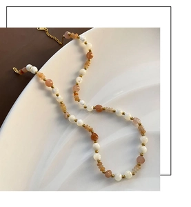 Detail of beaded strawberry crystal necklace with gold spacer beads on water-ripple tray