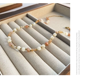 Close-up of strawberry quartz beaded necklace with gold spacers on grey velvet