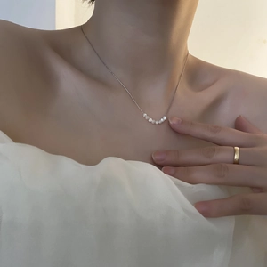 Collana in acciaio al titanio con sei perle bianche e anello d'oro su una modella