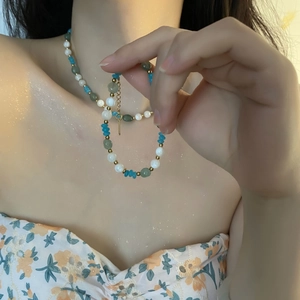 Handmade beaded necklace with natural blue stones, pearls and gold spacers on a model