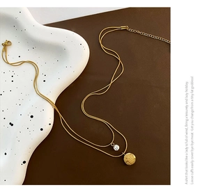Macro detail of gold double-layered necklace with Fu pendant and zircon stone inlay