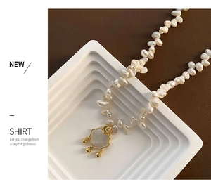 Detail of baroque pearl necklace featuring a gold cloud pendant with bell charms
