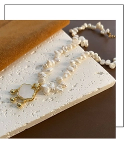 Macro detail of Baroque pearl necklace with golden cloud pendant and shell inlay