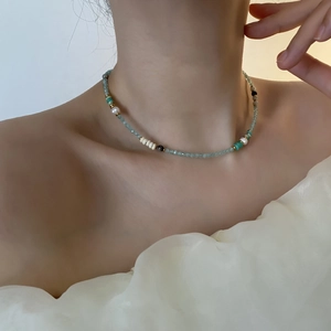 Elegante Perlenkette mit grünen Edelsteinen und weißen Perlen an weiblichem Modell