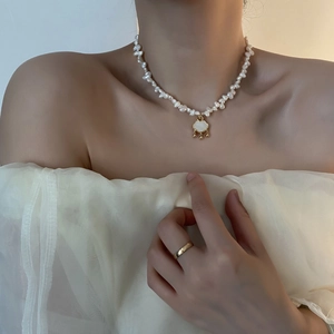 Baroque pearl necklace featuring a golden shell safety lock pendant on an elegant model