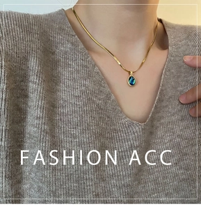 Detail of a golden snake chain necklace with an oval abalone shell teardrop pendant