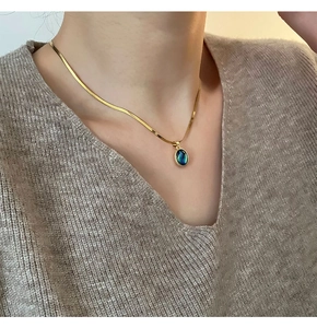 Detailed view of an oval abalone shell pendant on a gold snake chain necklace