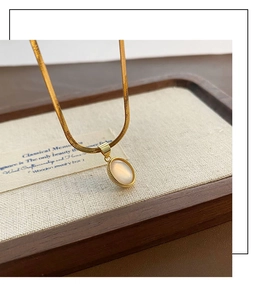 Detailed close-up of golden teardrop abalone shell pendant on a polished snake chain