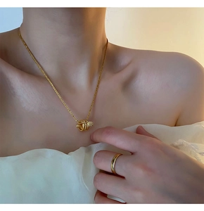 Dettaglio della collana con ciondolo a cilindro dorato e anello abbinato su modella