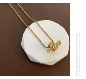 Dettaglio della collana dorata a spilla di balia con anello di zirconi