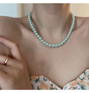 Detalle de un collar de perlas azul claro en el cuello con atuendo floral