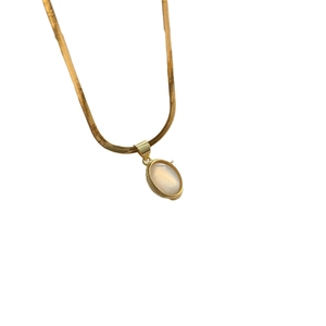 Gold snake chain necklace with abalone shell teardrop pendant on white background