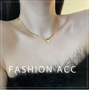 Détail d'un pendentif cœur doré avec nacre sur une chaîne serpent au style vintage