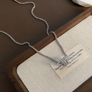 Collana con ciondolo a spilla di sicurezza e zirconi su vassoio in lino pregiato