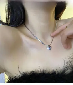 Détail d'un collier pendentif cœur en argent avec nacre sur une chaîne serpent