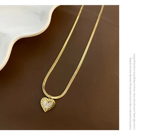 Détail du collier chaîne serpent dorée avec pendentif cœur et nacre blanche sertie