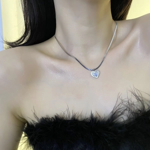 Pendentif cœur bleu sur chaîne serpent argentée porté par un mannequin de luxe