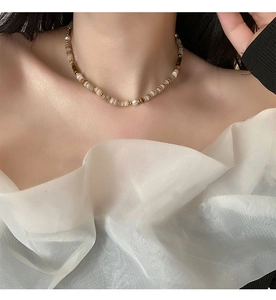 Gros plan d'un collier de perles vintage avec une perle blanche et des perles beiges