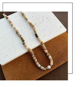 Détail de perles en pierre naturelle avec perles blanches et séparateurs dorés sur socle