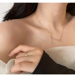 Close-up of rose gold heart pendant necklace and simple gold ring on a female model