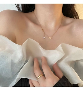 Close-up of rose gold heart pendant necklace and simple ring on model neck and hand