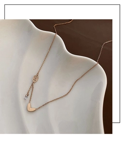 Detail of rose gold heart pendant necklace with zircon stone on a white ceramic plate