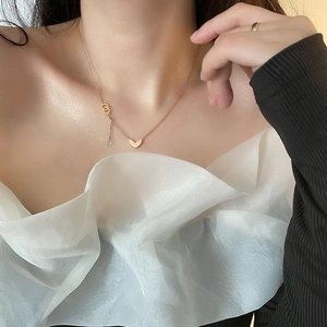 Rose gold heart pendant necklace with interlocked rings on a model's neck