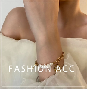 Close-up of baroque pearl chain bracelet with a gold smiling face pendant on wrist